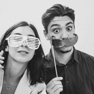 Collaborateurs souriants utilisant un photobooth moustache Movember avec impressions photo instantanées